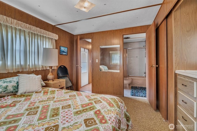 bedroom with light carpet, ensuite bath, and wooden walls