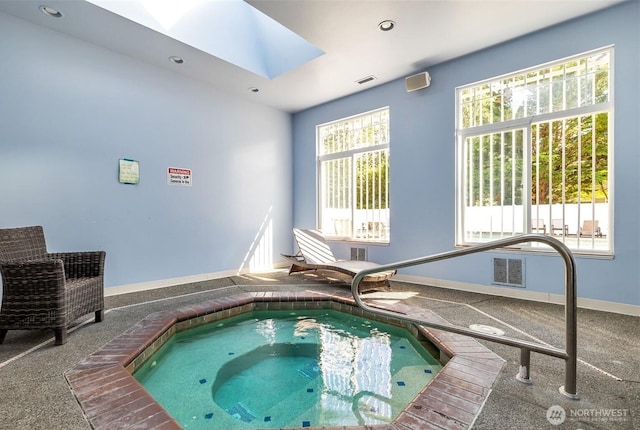 view of swimming pool with a skylight and an indoor in ground hot tub