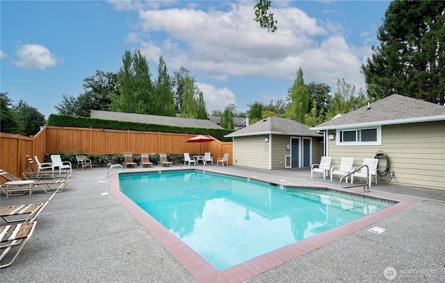 view of swimming pool featuring an outbuilding, a patio area, fence, and a fenced in pool