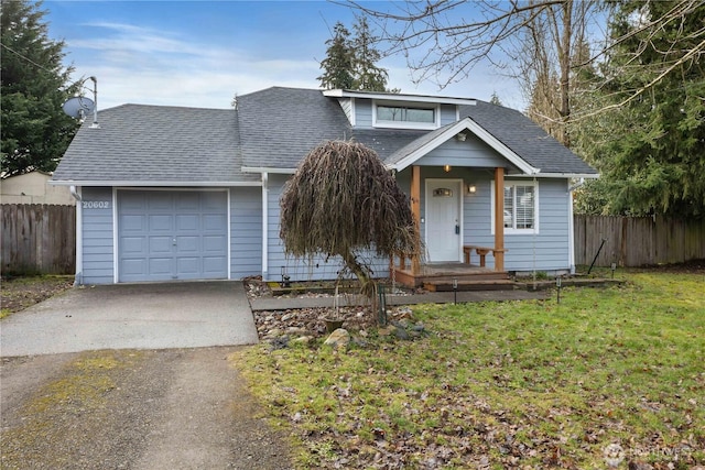 view of front of home featuring an attached garage, fence, concrete driveway, roof with shingles, and a front yard