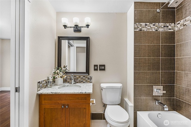 full bathroom with vanity, tiled shower / bath, toilet, and backsplash