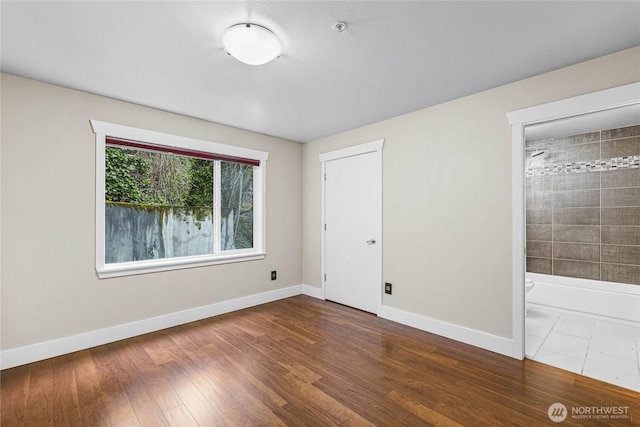 unfurnished bedroom with ensuite bath and dark hardwood / wood-style flooring