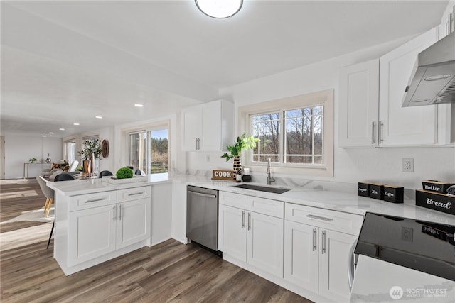 kitchen with white cabinetry, kitchen peninsula, stainless steel dishwasher, and wall chimney range hood