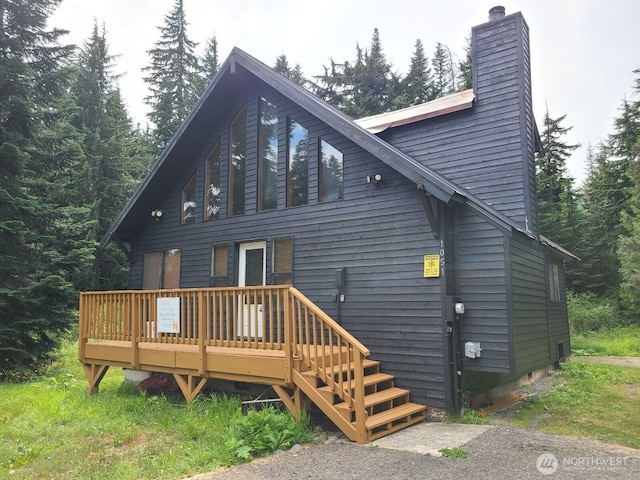 rear view of property featuring a chimney and a wooden deck