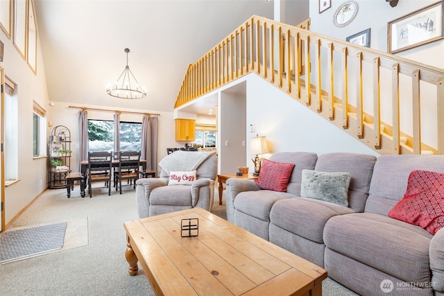 living room with carpet floors, a high ceiling, a chandelier, baseboards, and stairs