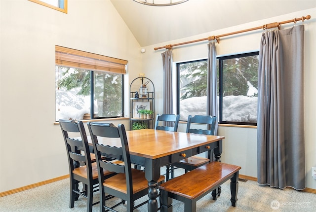 dining space with high vaulted ceiling, light colored carpet, and baseboards