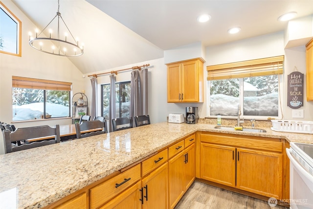 kitchen featuring light stone counters, hanging light fixtures, electric range, a sink, and a peninsula