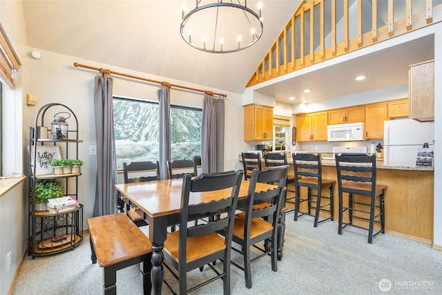 dining area with high vaulted ceiling, recessed lighting, light colored carpet, and a notable chandelier