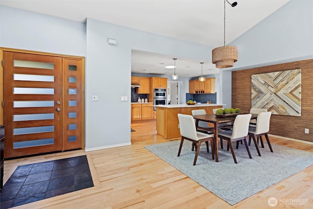 dining room featuring light wood-type flooring and vaulted ceiling