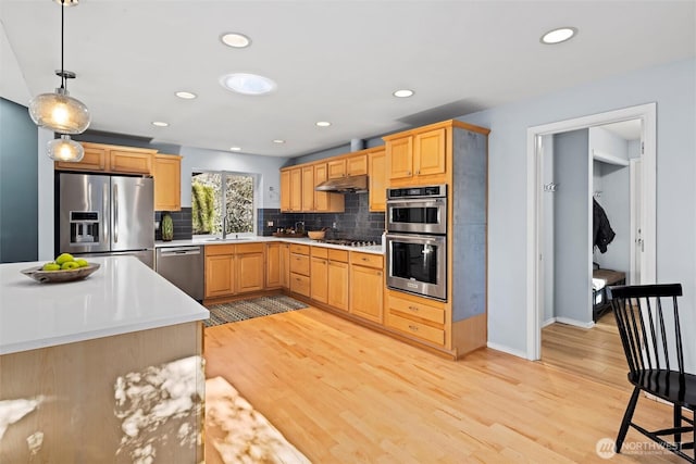 kitchen with appliances with stainless steel finishes, hanging light fixtures, backsplash, light brown cabinets, and sink