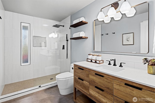 bathroom with baseboard heating, vanity, a tile shower, and toilet