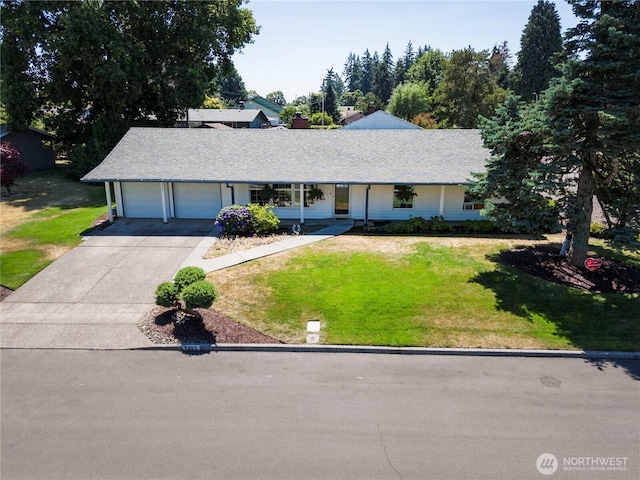 ranch-style home featuring a garage, concrete driveway, roof with shingles, and a front yard