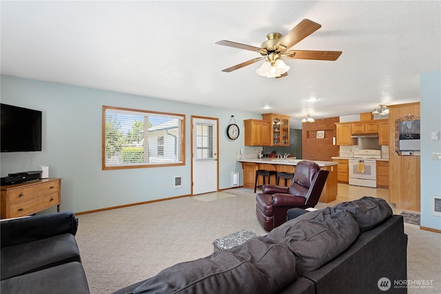 living room with a ceiling fan, light carpet, visible vents, and baseboards