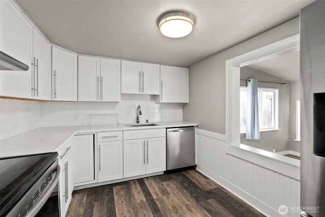 kitchen featuring appliances with stainless steel finishes, backsplash, dark hardwood / wood-style flooring, sink, and white cabinetry