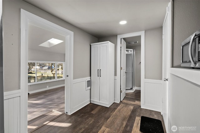 corridor with dark wood-type flooring and a skylight