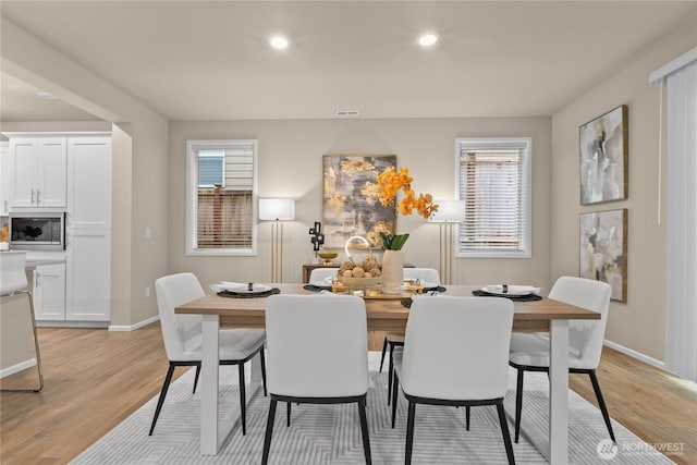 dining area featuring baseboards, light wood finished floors, and a healthy amount of sunlight