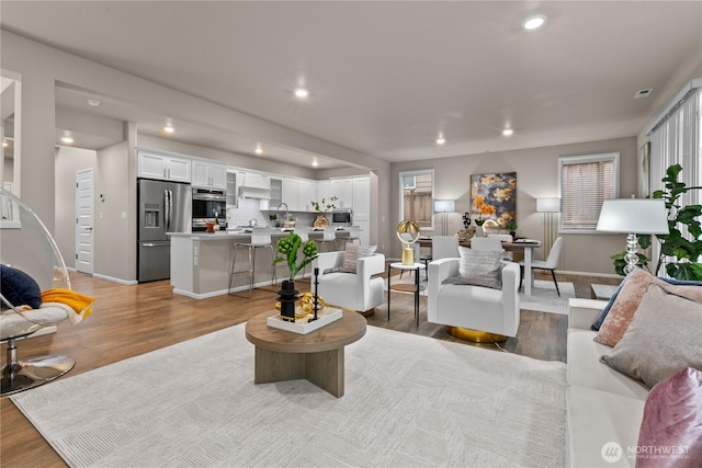 living area featuring light wood-type flooring, visible vents, baseboards, and recessed lighting