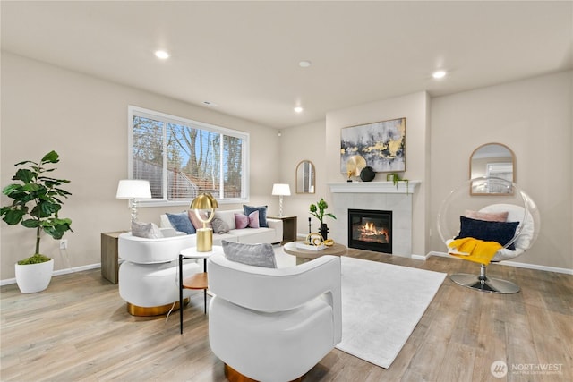 living room featuring baseboards, light wood finished floors, a fireplace, and recessed lighting