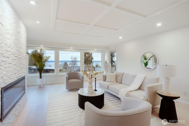 living room featuring coffered ceiling, light hardwood / wood-style floors, and a fireplace