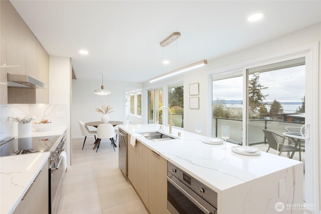 kitchen with hanging light fixtures, stainless steel appliances, light brown cabinetry, and sink