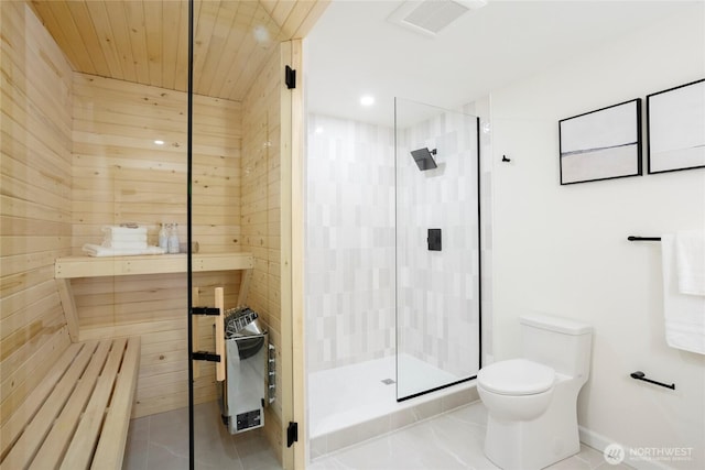 bathroom with a tile shower, tile patterned flooring, wood walls, and toilet