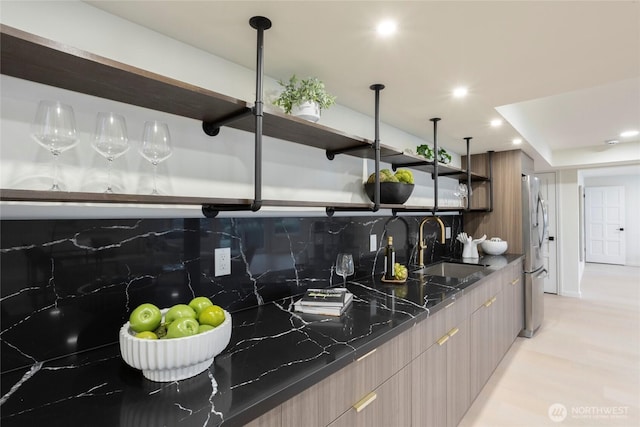 kitchen with decorative light fixtures, stainless steel refrigerator, sink, dark stone counters, and decorative backsplash