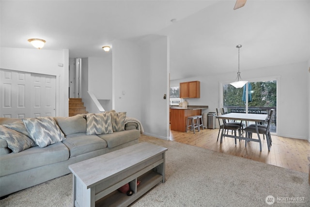 living room with light wood-style floors, baseboards, and stairs