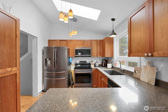 kitchen with light stone counters, pendant lighting, stainless steel appliances, and a sink