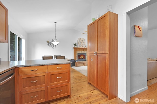 kitchen with open floor plan, hanging light fixtures, a lit fireplace, and stainless steel dishwasher