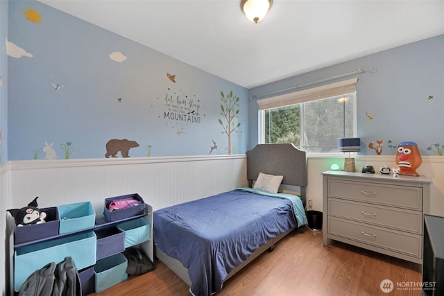 bedroom featuring light wood-type flooring and wainscoting