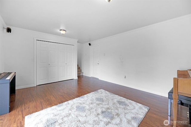 bedroom with dark wood-style floors, a closet, ornamental molding, and baseboards