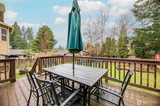 wooden terrace featuring outdoor dining space, a fenced backyard, and a yard