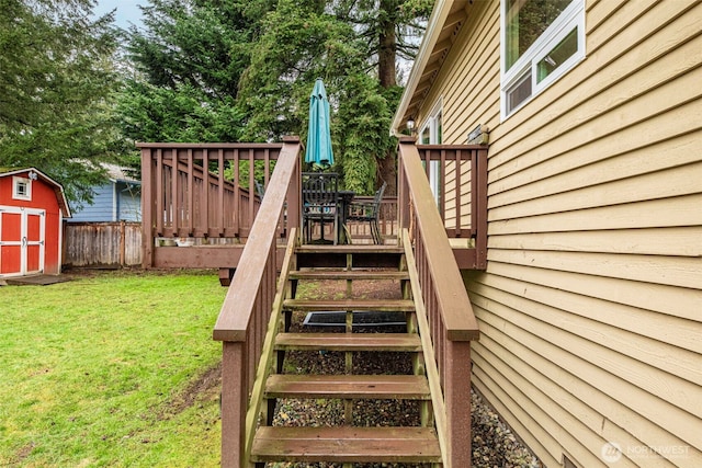 wooden terrace featuring fence, stairs, a yard, a shed, and outdoor dining space