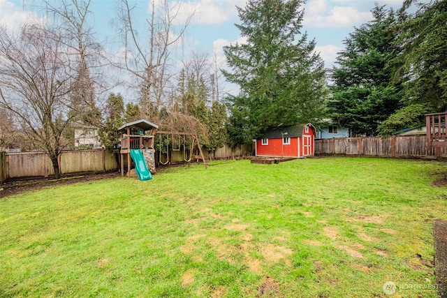 view of yard featuring an outbuilding, a playground, a fenced backyard, and a storage shed