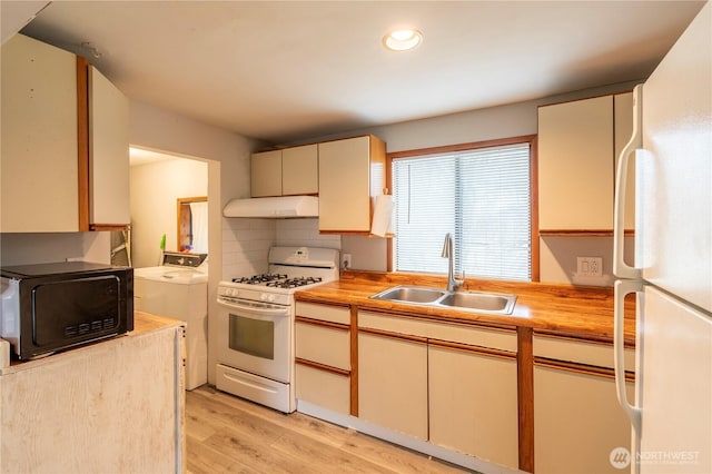 kitchen with white appliances, washing machine and dryer, sink, light wood-type flooring, and decorative backsplash