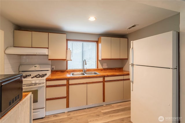 kitchen with butcher block countertops, sink, white appliances, and cream cabinets