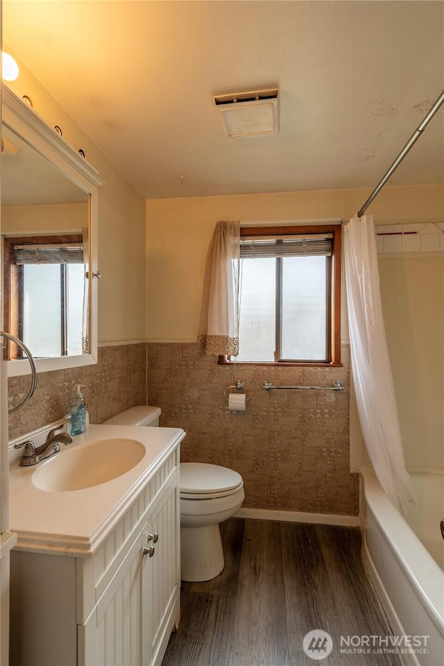 full bathroom featuring a wealth of natural light, wood-type flooring, toilet, and shower / bath combination with curtain