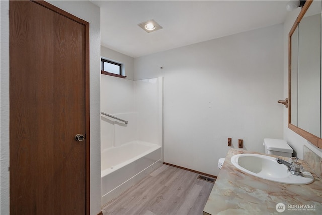 full bathroom with visible vents, toilet, wood finished floors, vanity, and shower / washtub combination