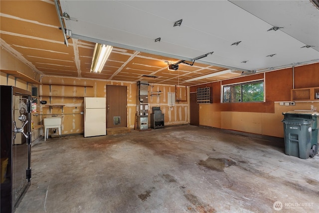 garage featuring a garage door opener, a sink, and freestanding refrigerator