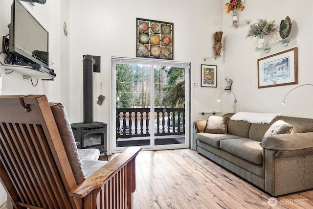 living room with a high ceiling, a wood stove, and light wood-style floors