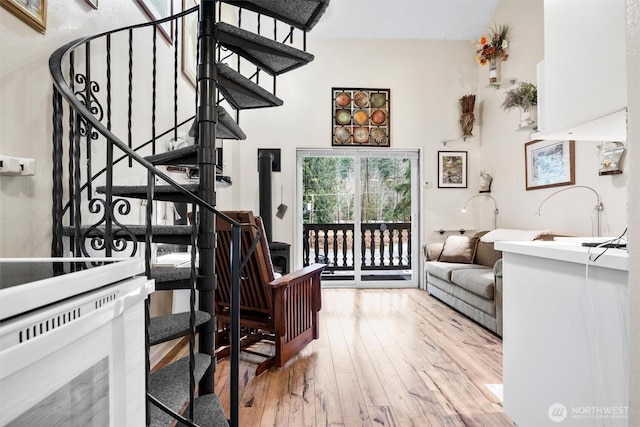 interior space with wood-type flooring, a towering ceiling, and stairs