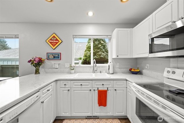 kitchen with sink, white appliances, and white cabinets