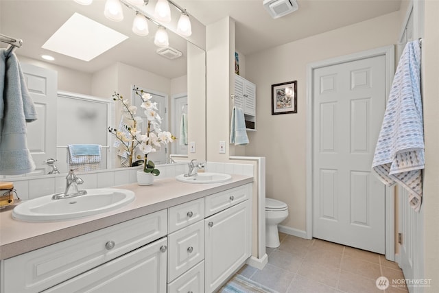 bathroom with a shower with shower door, tile patterned floors, toilet, a skylight, and vanity