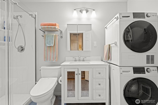 bathroom with toilet, stacked washer / drying machine, an enclosed shower, and vanity