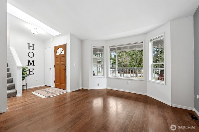 entryway with stairs, wood finished floors, baseboards, a skylight, and visible vents