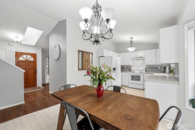 dining area with lofted ceiling, a chandelier, and light wood-type flooring