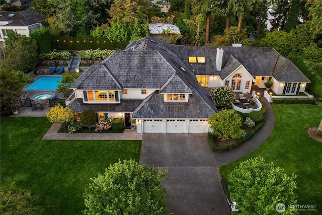 view of front facade with a front yard, driveway, a chimney, and a patio