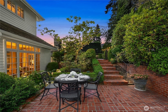 patio terrace at dusk featuring outdoor dining area and stairway