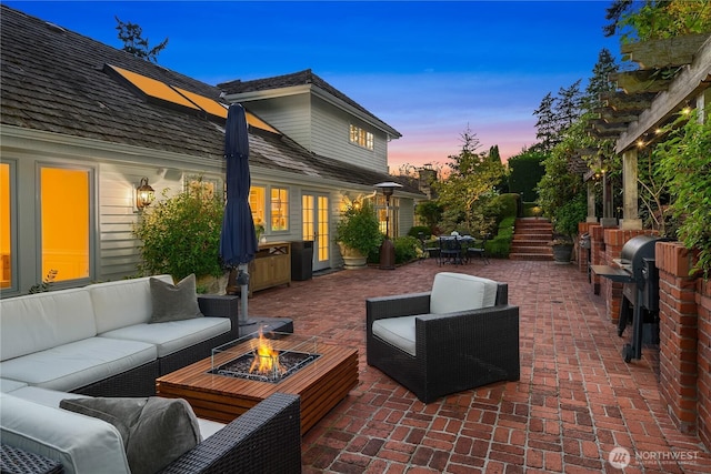 patio terrace at dusk featuring outdoor dining space, stairway, area for grilling, and an outdoor living space with a fire pit