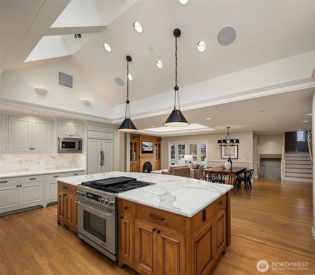 kitchen featuring built in appliances, hanging light fixtures, a kitchen island, and light wood-style flooring